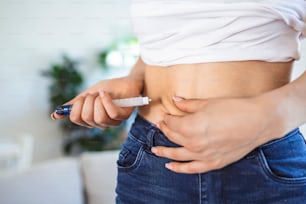 A diabetic patient using insulin pen for making an insulin injection at home. Young woman control diabetes. Diabetic lifestyle