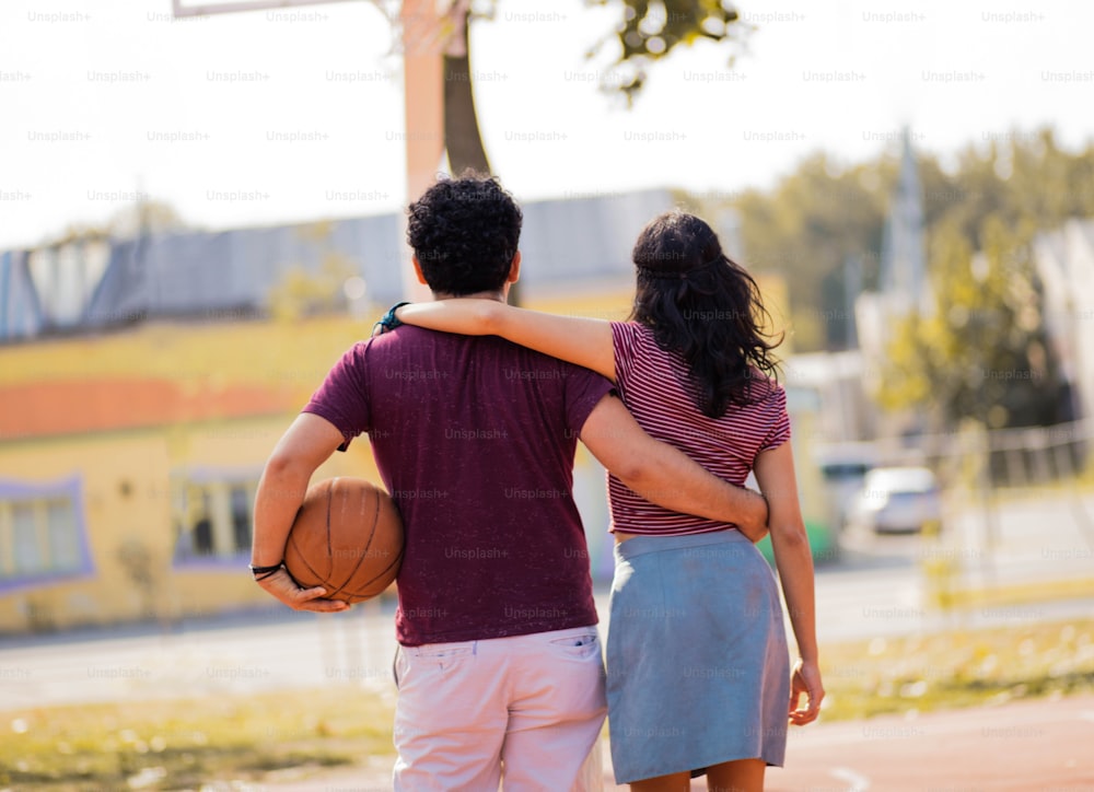Couple with ball on basketball court.
