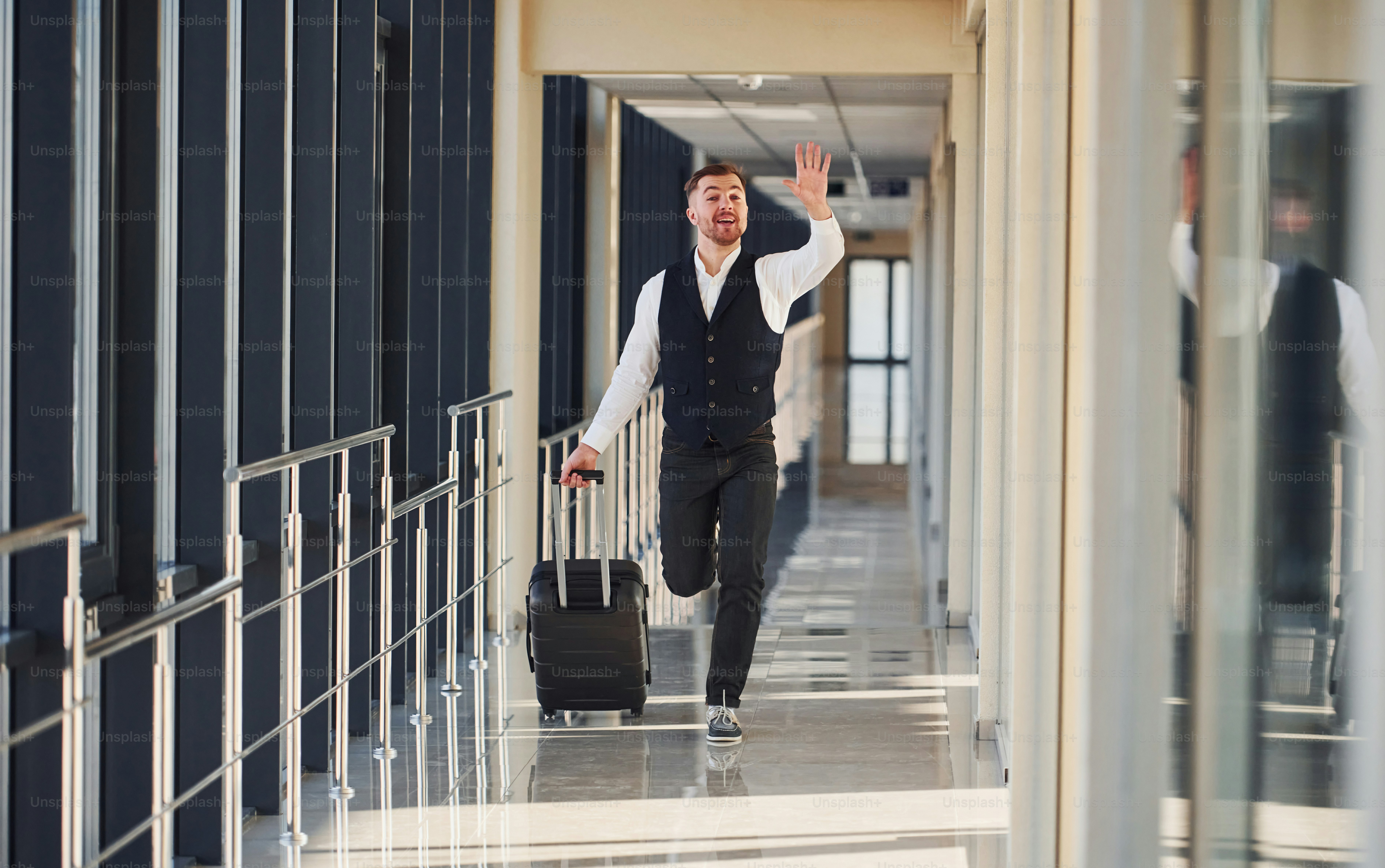 Man in formal clothes and with baggage is running forward and busy for a plane.