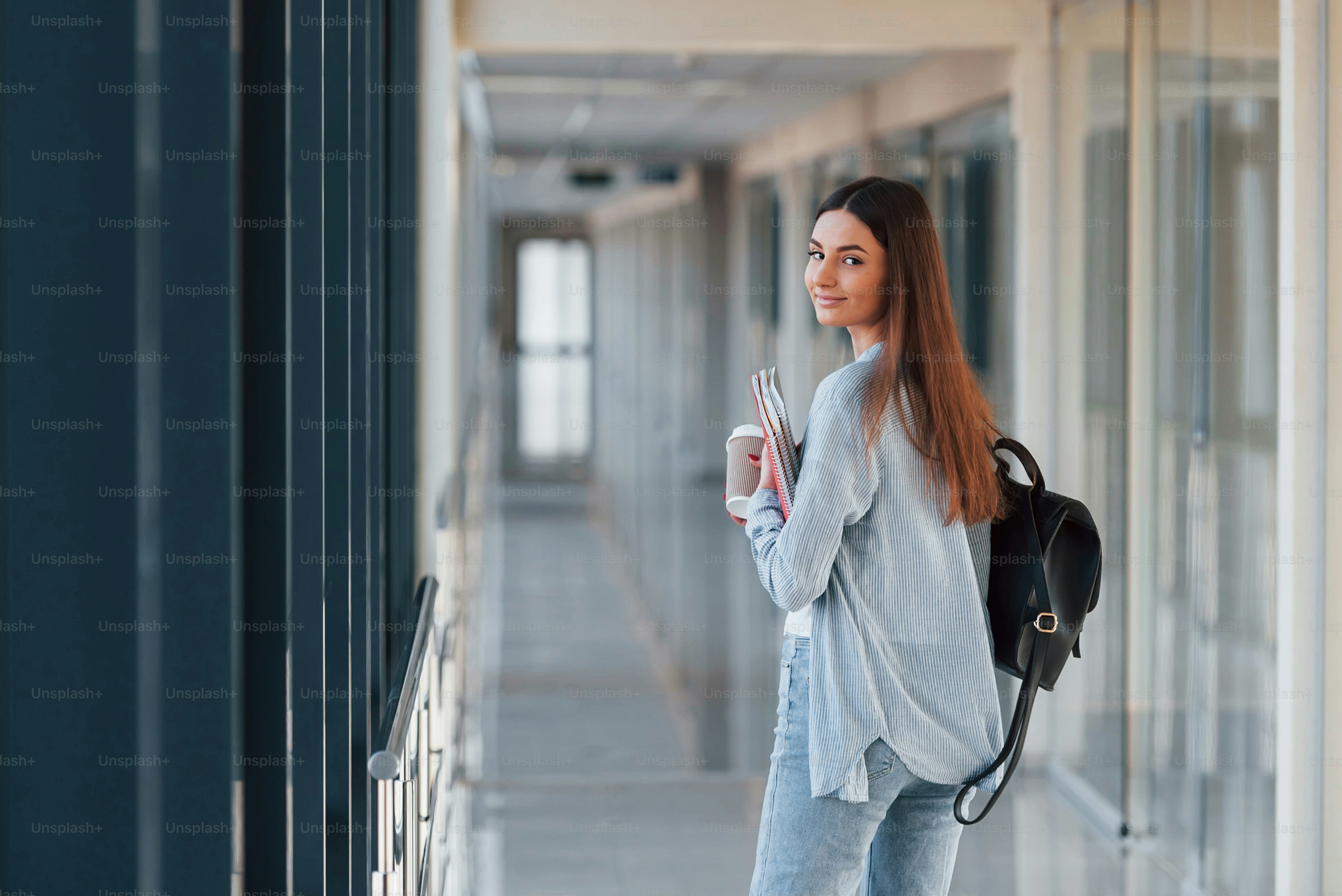 大学の廊下でメモ帳を持っている女子学生の後ろ姿。