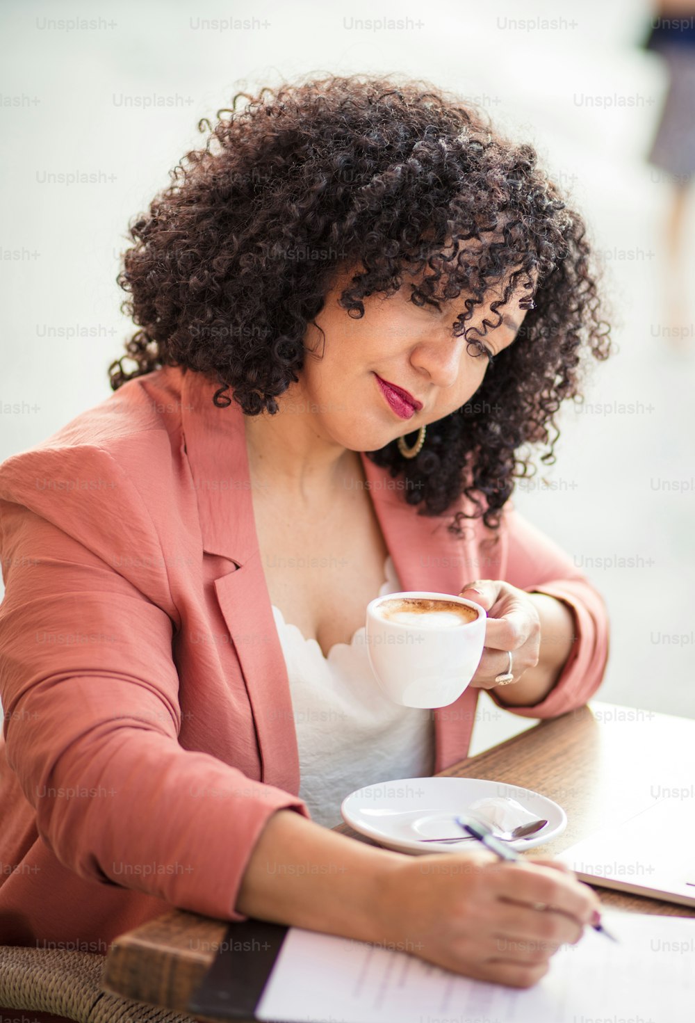 Geschäftsfrau sitzt im Café und schreibt auf ein Dokument.