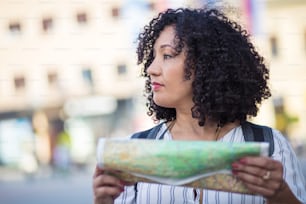 Lost in the city. Woman standing on street with map in hands.