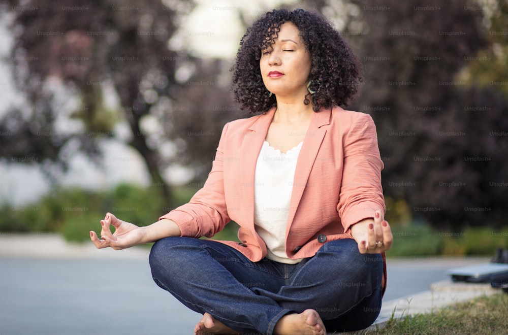 Dia relaxante.  Mulher de negócios que trabalha yoga na rua.