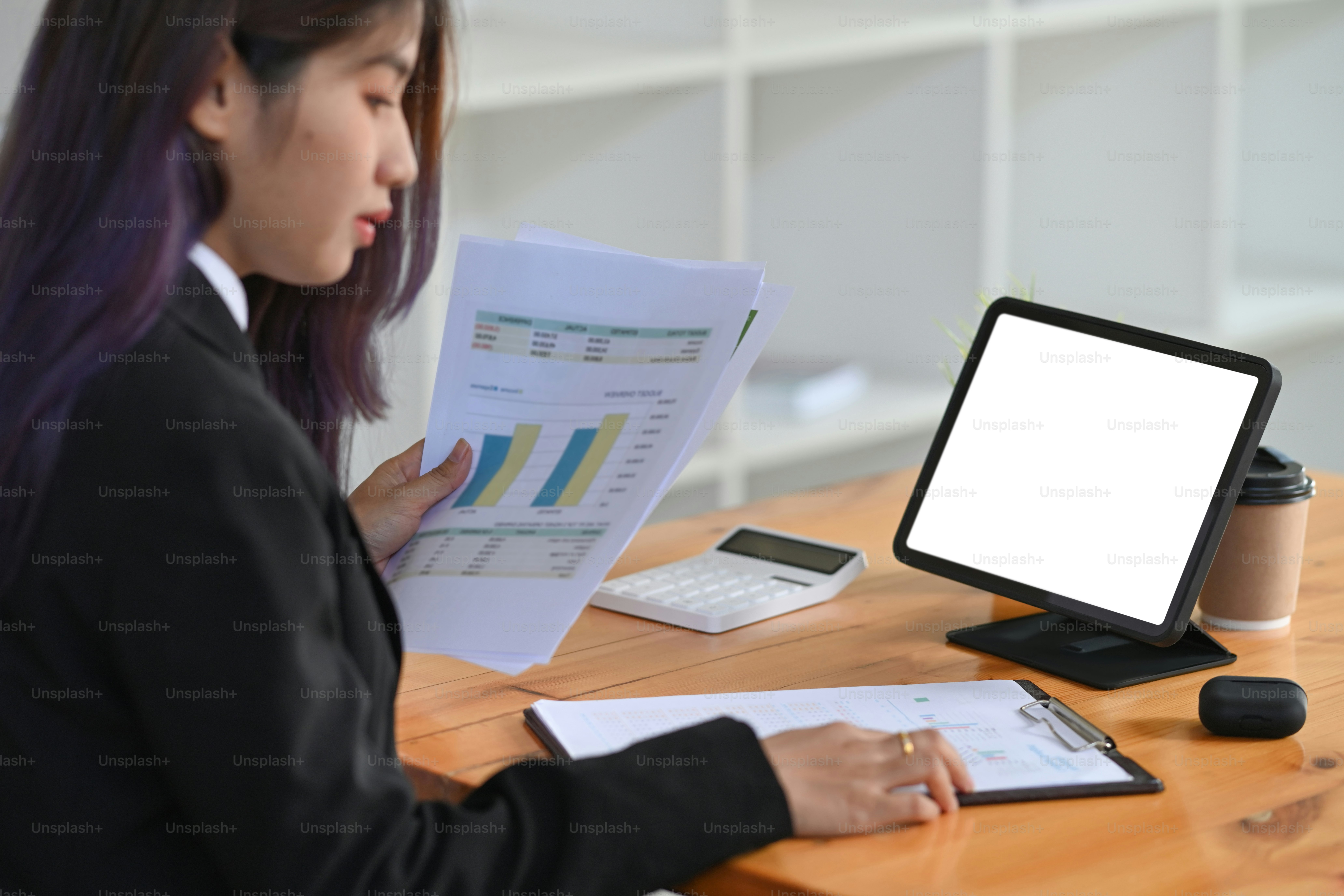 Businesswoman working with computer tablet and analyzing documents at ...