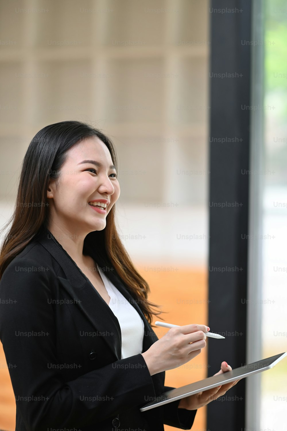Portrait of smiling businesswoman standing in office and holding digital tablet.
