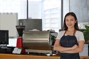 Small business owner standing with arms crossed at counter and smiling to camera.