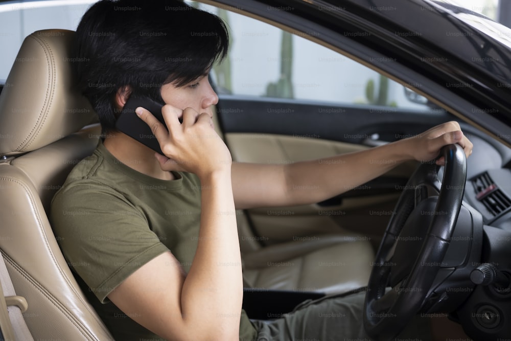 차를 운전하는 동안 휴대 전화로 이야기하는 청년.