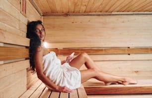 Joven hermosa mujer descansa en la sauna. Concepción del cuidado corporal.