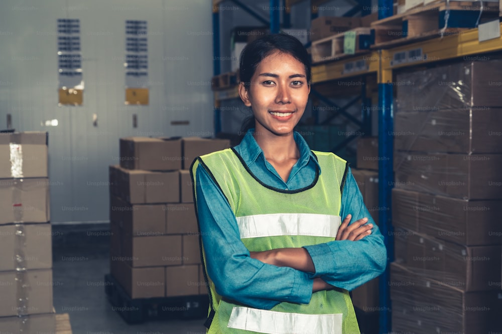 Ritratto di giovane magazziniere sorridente nel magazzino. Concetto di business della logistica, della catena di approvvigionamento e del magazzino.