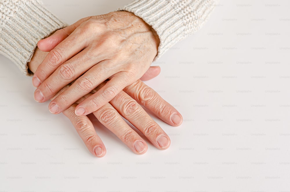Hände einer älteren Frau auf weißem Hintergrund. Nahaufnahme, Kopierraum.