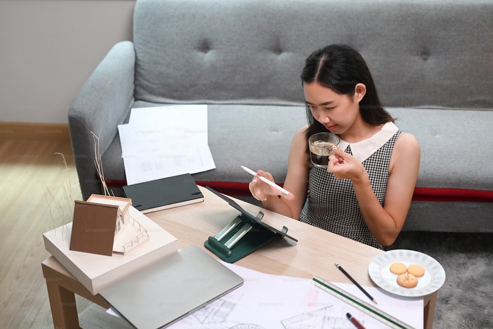 Architect woman working with computer tablet and blueprint in living room.