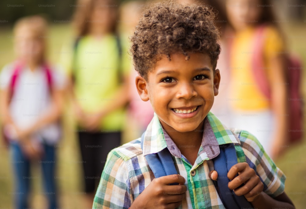 Large group of school kids in nature. Portrait of school boy. Focus is on foreground.