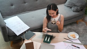 Architektin, die mit digitalen Tablets und Blaupausen arbeitet, während sie im Wohnzimmer sitzt.