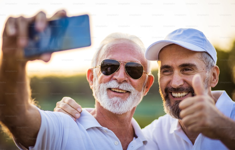 Two seniors golfers taking self portrait with phone.