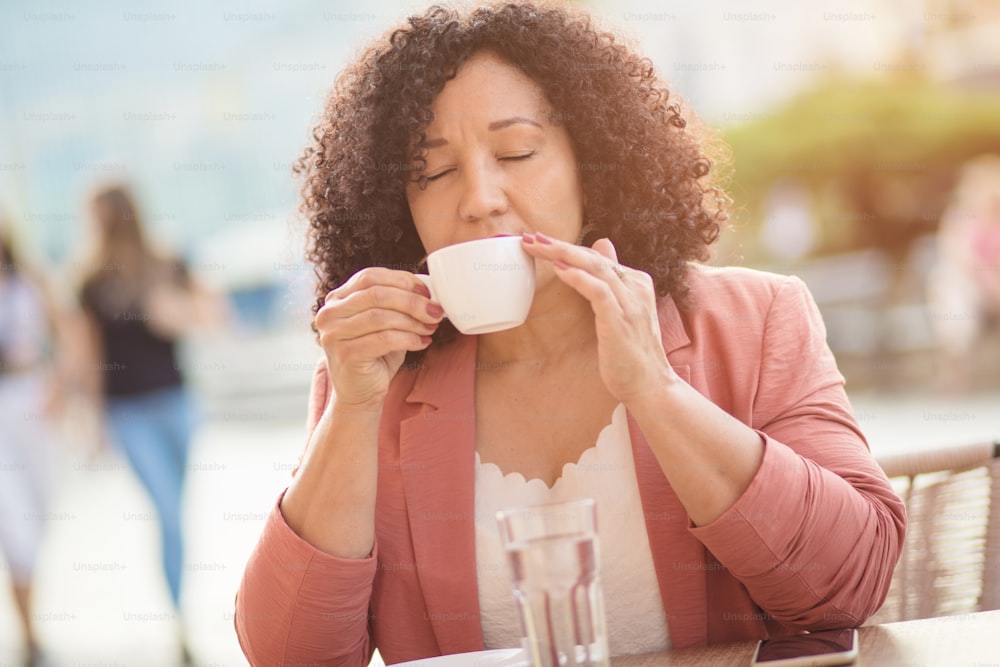 Hora do café.  Retrato da mulher que bebe café na rua.