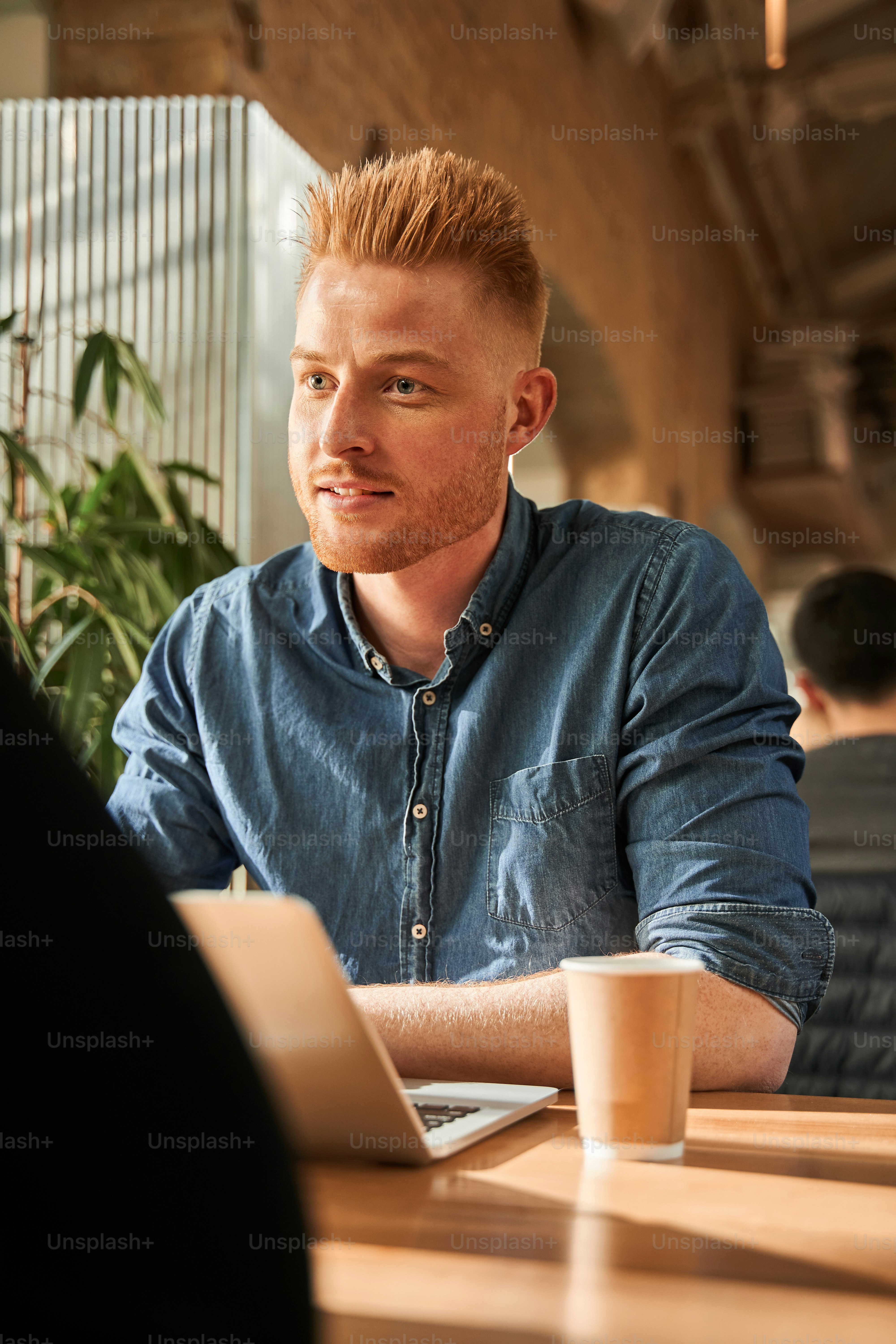 Job conversation. Waist up portrait view of the caucasian unshaven man sitting at the table indoors and chatting with his female colleague while working at the cafe. Interview concept