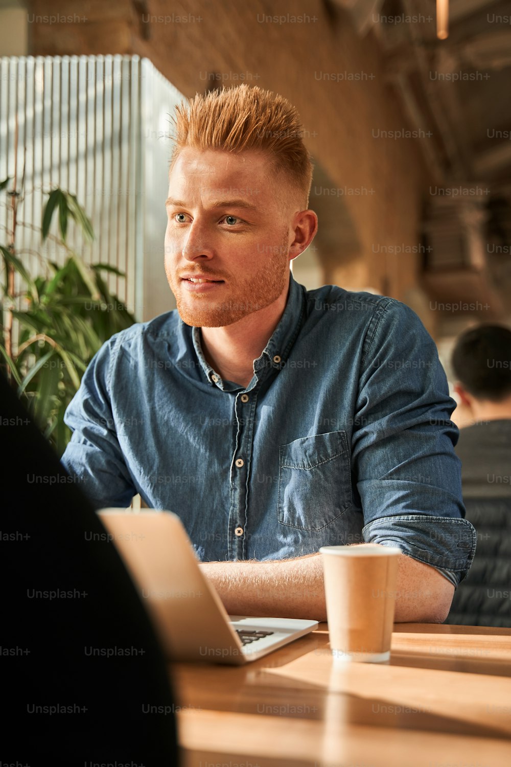 Conversazione di lavoro. Vista verticale dalla vita in su dell'uomo caucasico non rasato seduto al tavolo all'interno e chiacchierando con la sua collega mentre lavora al bar. Concetto di intervista