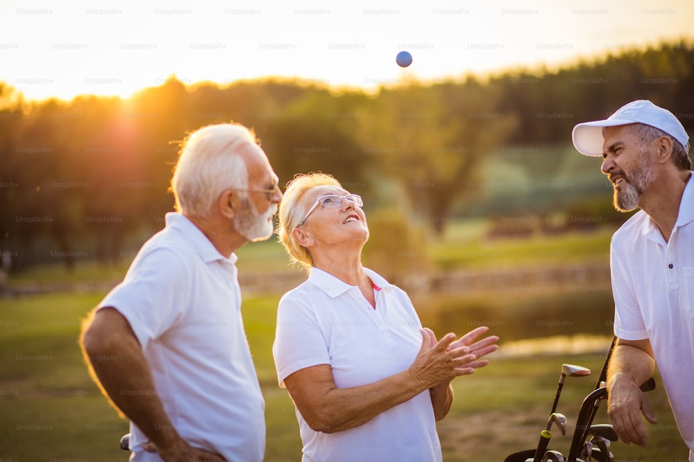 Drei Seniorengolfer unterhalten sich auf dem Golfplatz.