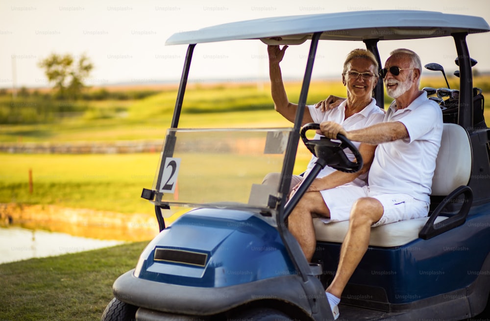 Coppia di golfisti anziani in golf car.