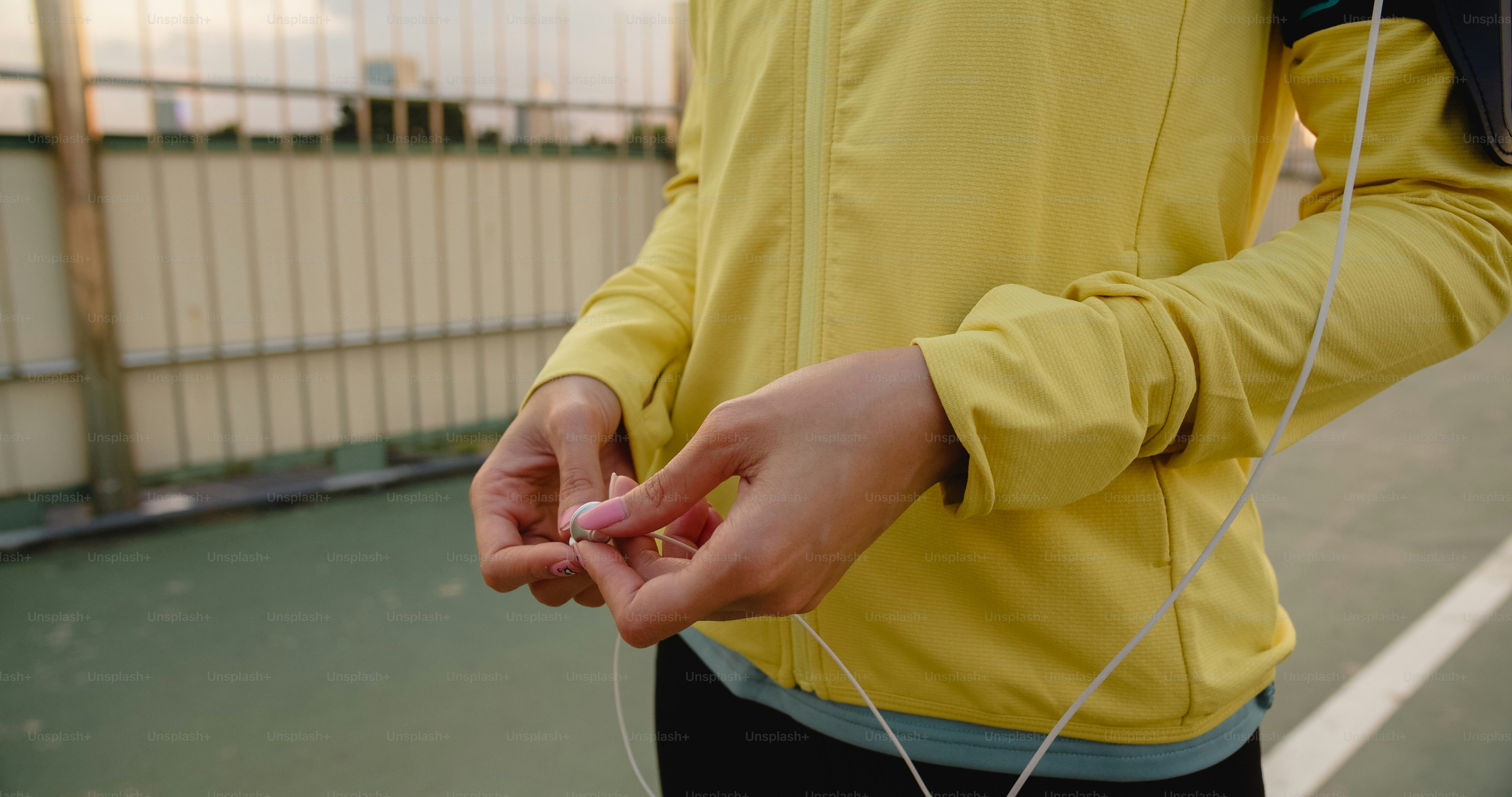 Bela jovem atleta da Ásia se exercita usando o smartphone para ouvir música enquanto corre no ambiente urbano. Adolescente coreana vestindo roupas esportivas na ponte da passarela no início da manhã.