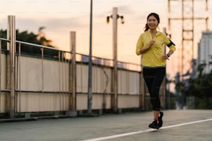 Beautiful young Asia athlete lady running exercises work out in urban environment. Japanese teen girl wearing sports clothes on walkway bridge in early morning. Lifestyle active sporty in city.