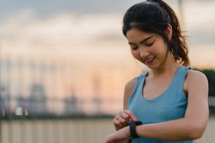 Beautiful young Asia athlete lady exercises doing stretch work out in urban environment. Japanese teen girl wearing sports clothes on walkway bridge in early morning. Lifestyle active sporty in city.