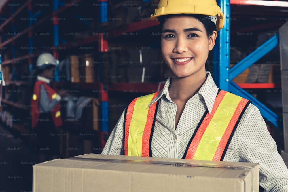 Retrato da jovem asiática mulher trabalhador do armazém sorrindo no armazém. Conceito de negócio de logística, supply chain e armazém.