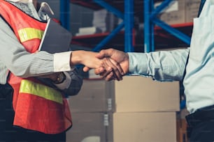Warehouse worker handshake with manager in storehouse . Logistics , supply chain and warehouse business concept .