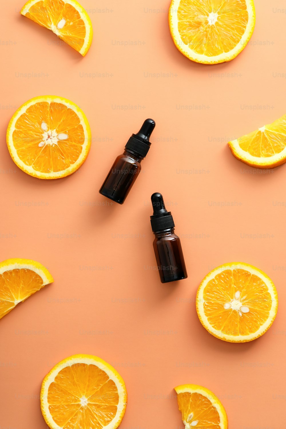 Vitamin C serum dropper bottles with sliced orange top view. Natural beauty products design.
