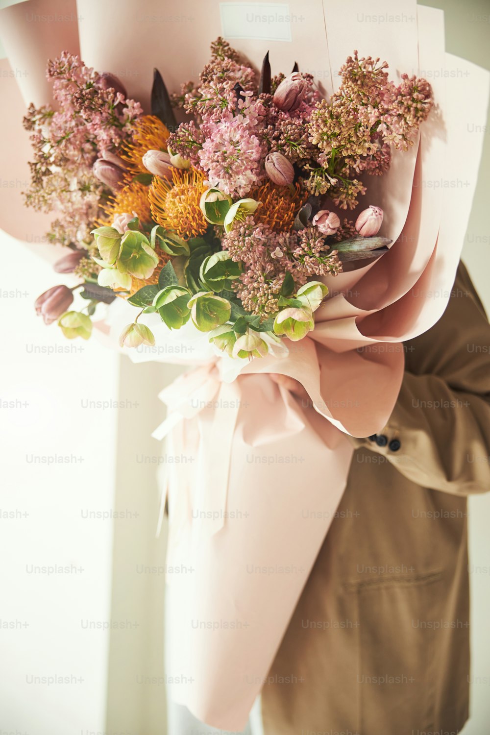 Photo recadrée d’un client faisant la démonstration d’un bouquet de fleurs mélangées enveloppé dans du papier d’emballage et attaché avec un ruban de soie