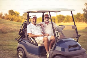 Dos amigos mayores viajan en un carrito de golf.