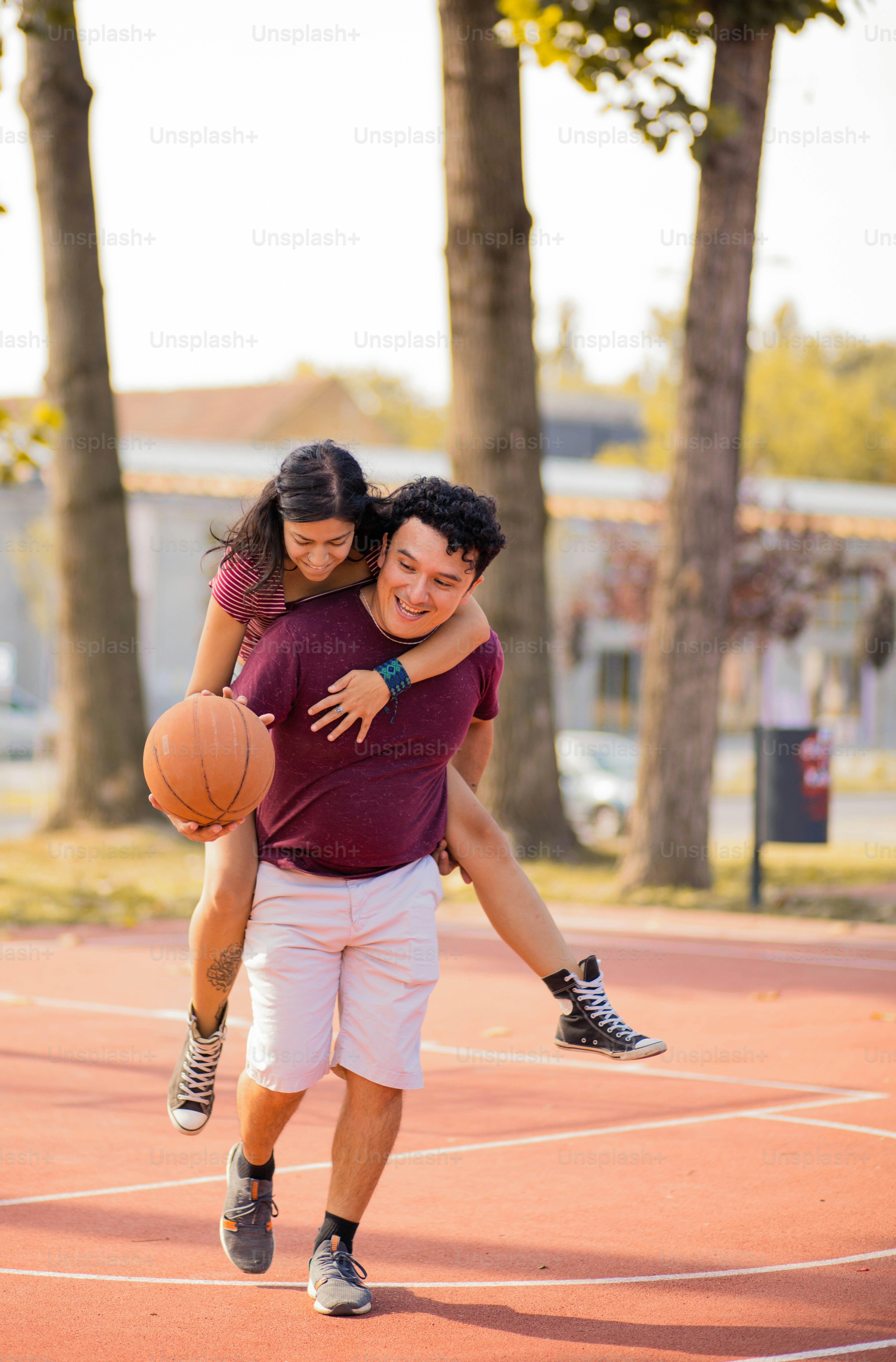 Jeune couple jouant au basket-ball. Homme portant une fille sur le dos de ferroutage.