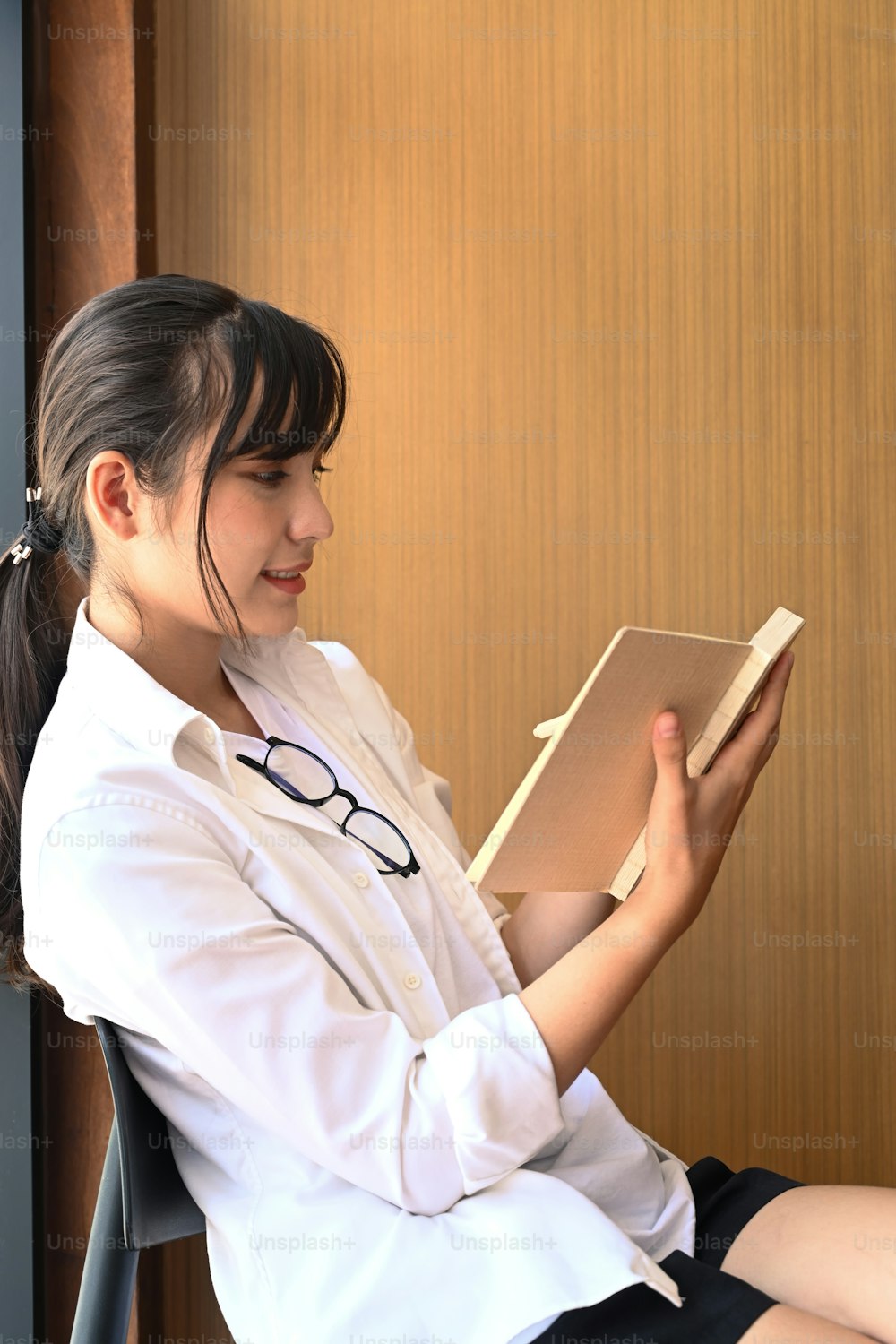 Portrait of peaceful young woman reading book in library.