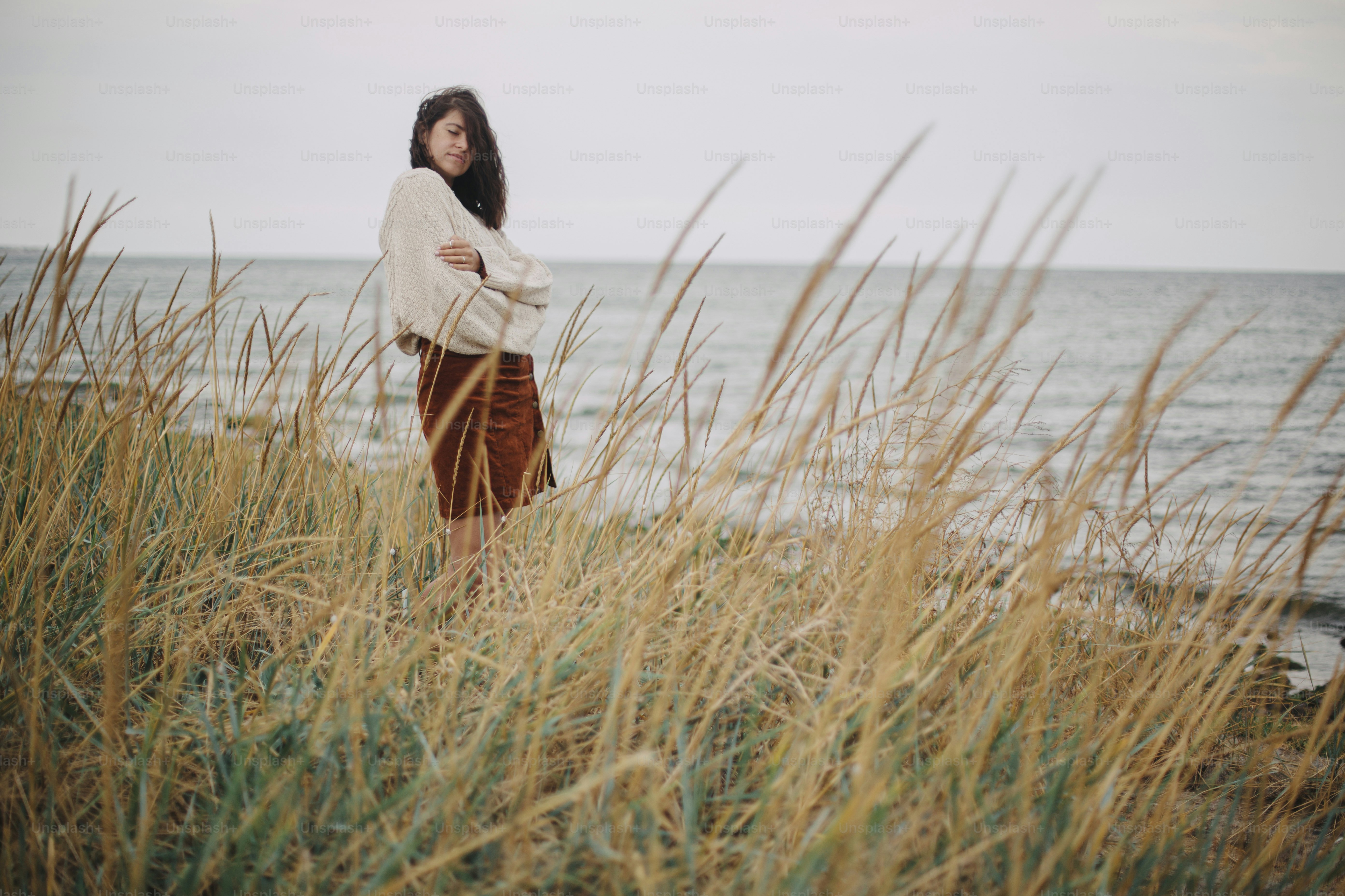 Beautiful stylish woman with windy hair in knitted sweater posing among ...