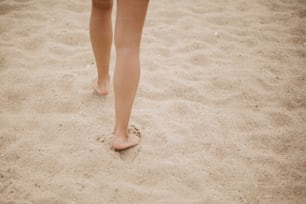Hermosas piernas de mujer descalzas caminando en la playa de arena, estado de ánimo de vacaciones despreocupadas. Mujer joven con estilo relajándose en la costa, vista recortada. Playa de verano. Espacio para el texto