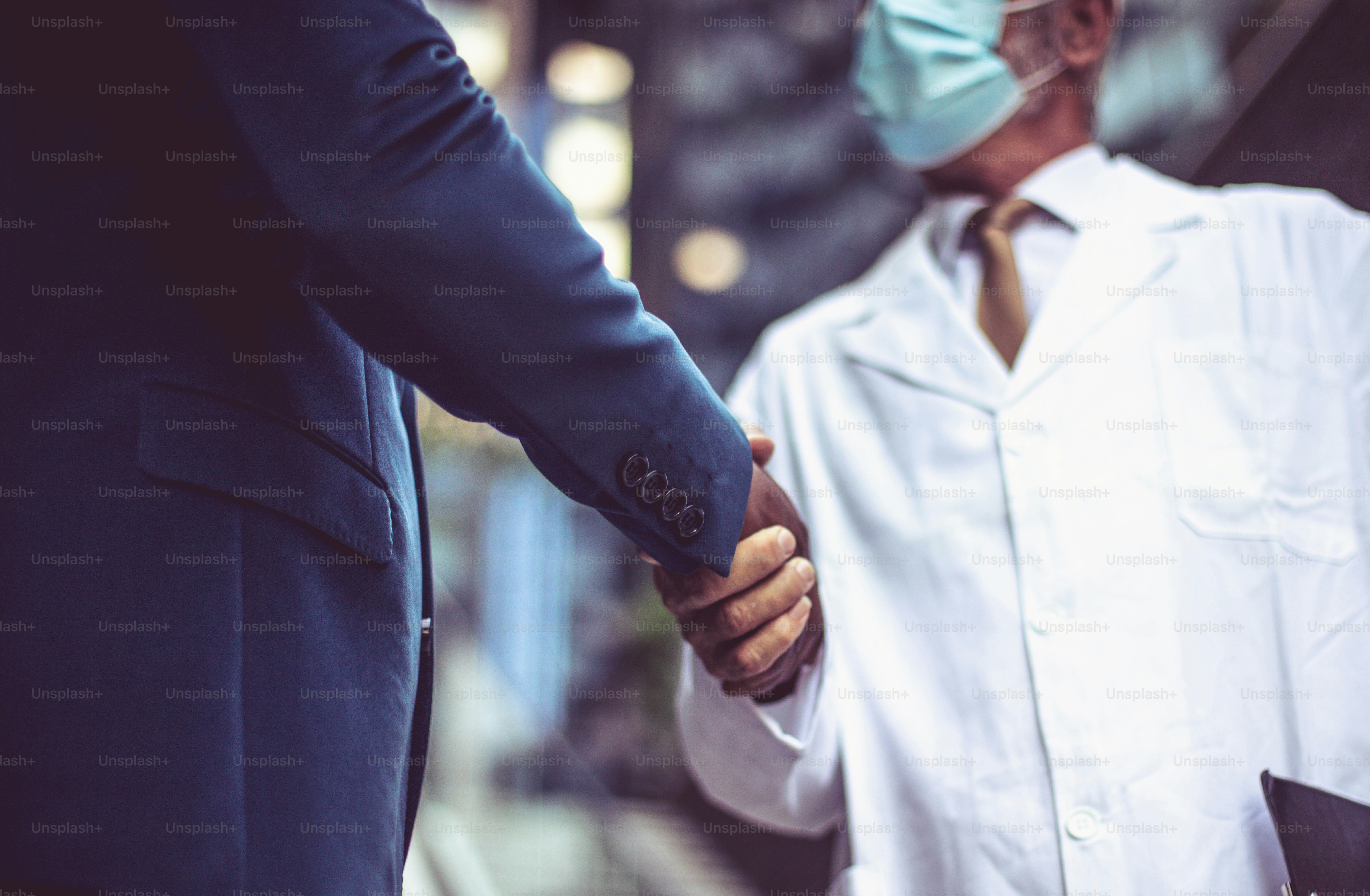 Business man, and doctor on street handshaking. Wearing protective mask. Focus in hands.