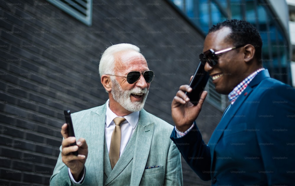 Two business men talking on the street and using mobile.