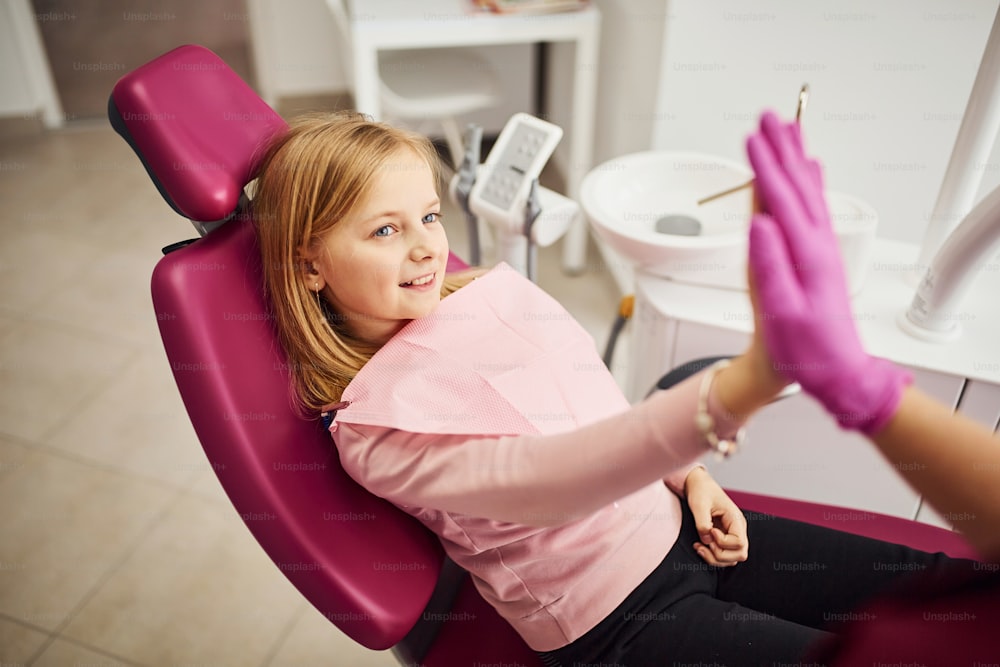 하이파이브를 제공합니다. 클리닉에서 치과 의사를 방문하는 어린 소녀. 구강 학의 개념.