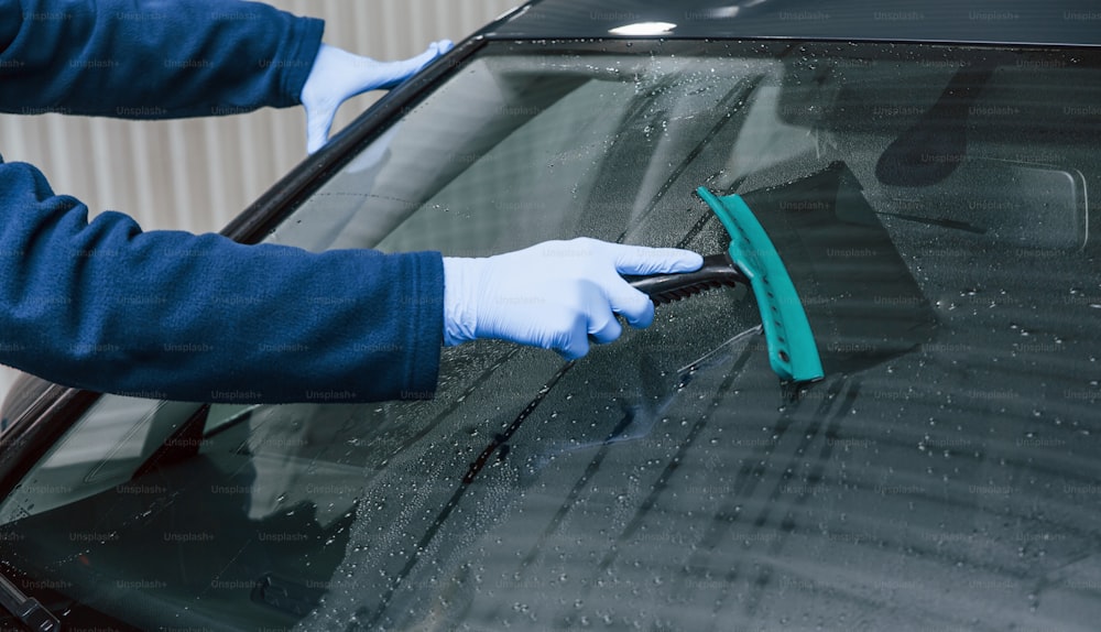 制服を着た男性労働者が新しい近代的な車を洗っています。サービスの概念。