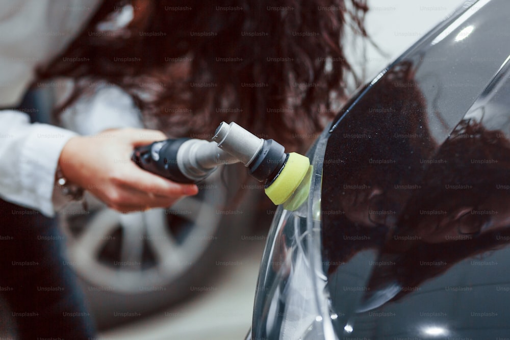 Woman with equipment cleaning modern automobile. Conception of service.