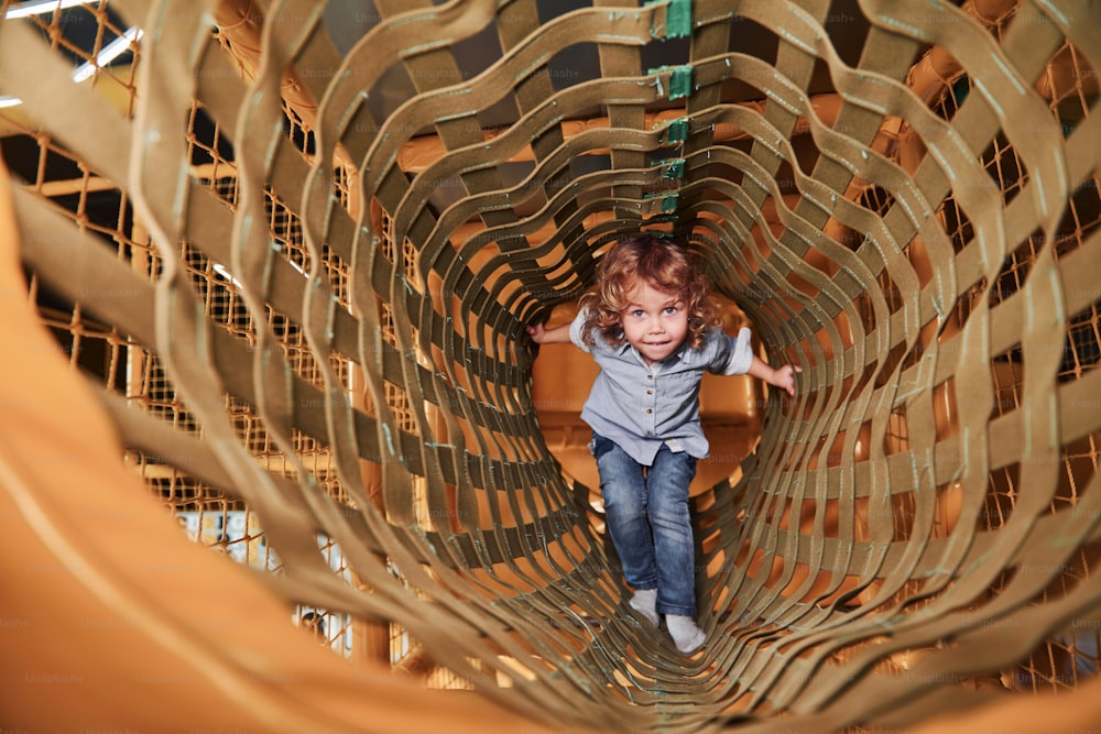 Child have fun in playroom by going through the wooden cage.