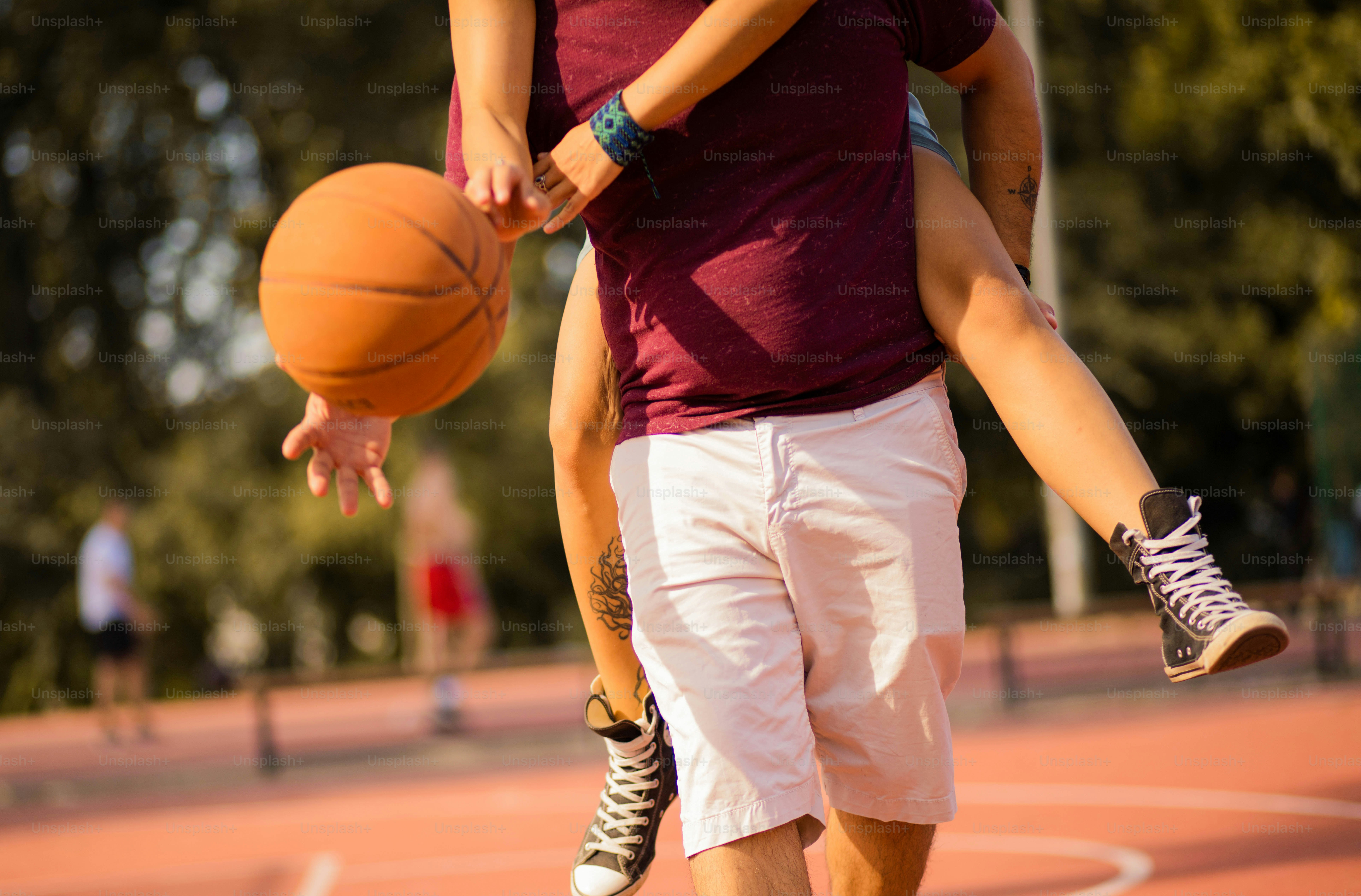 Jeune couple jouant au basket-ball. Homme portant une fille sur le dos de ferroutage.