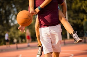 バスケットボールをする若いカップル。おんぶに女の子を乗せた男。