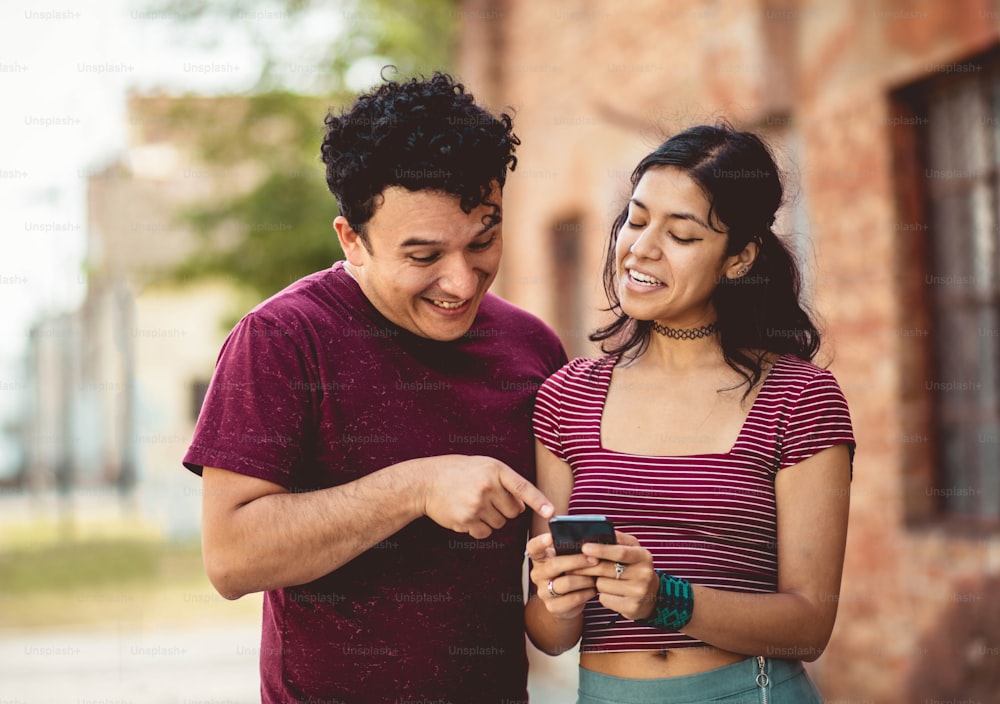 Young smiling couple on street using mobile.