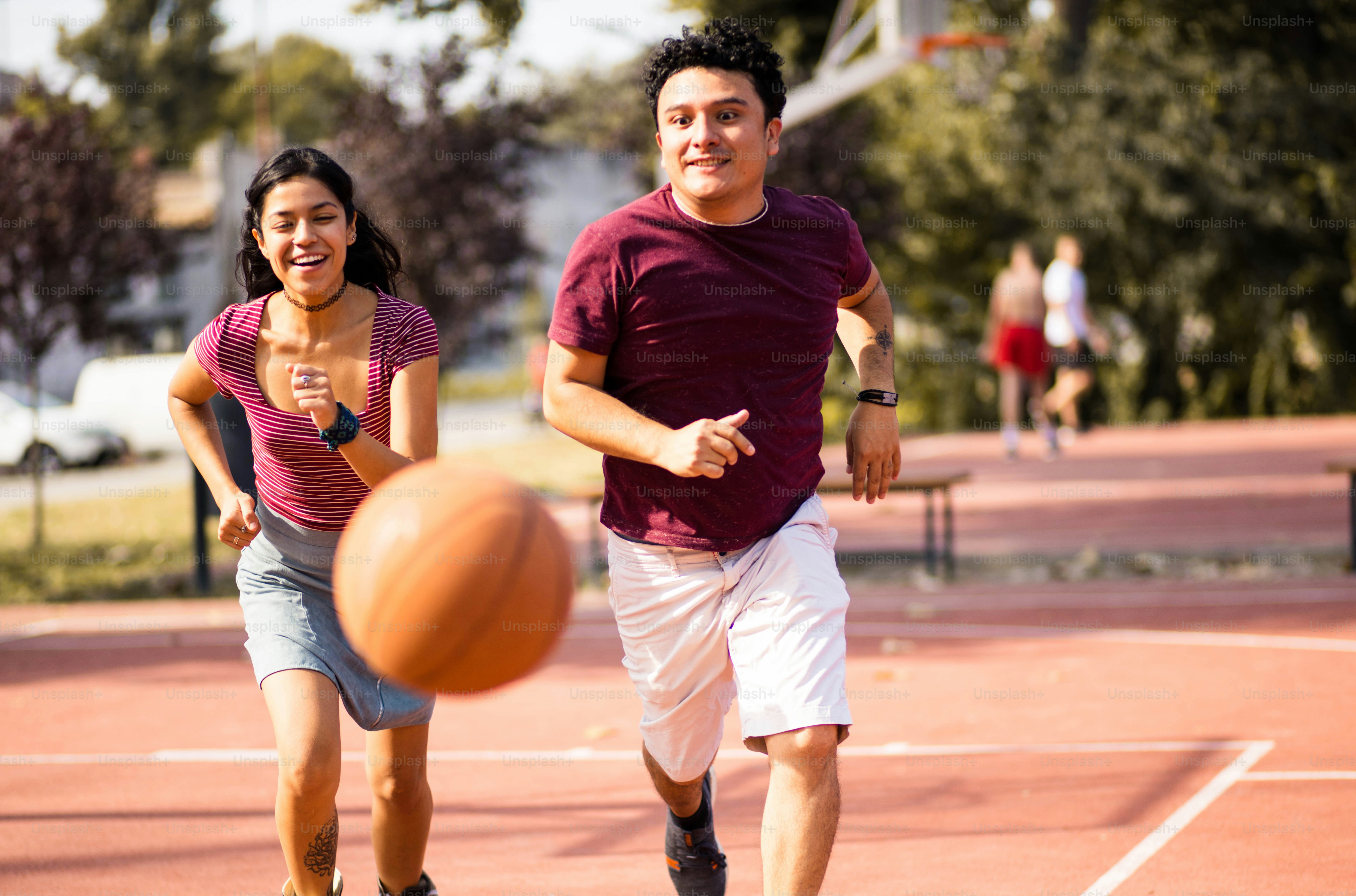 Jeune couple jouant au basket-ball. L’accent est mis sur la femme et l’homme.