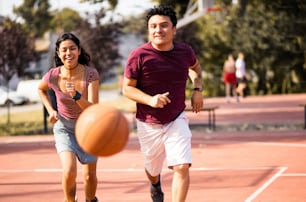 Young couple playing basketball. Focus is on woman and man.