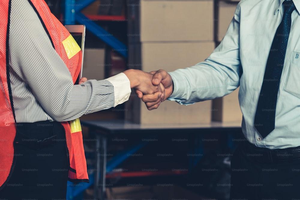Warehouse worker handshake with manager in storehouse . Logistics , supply chain and warehouse business concept .
