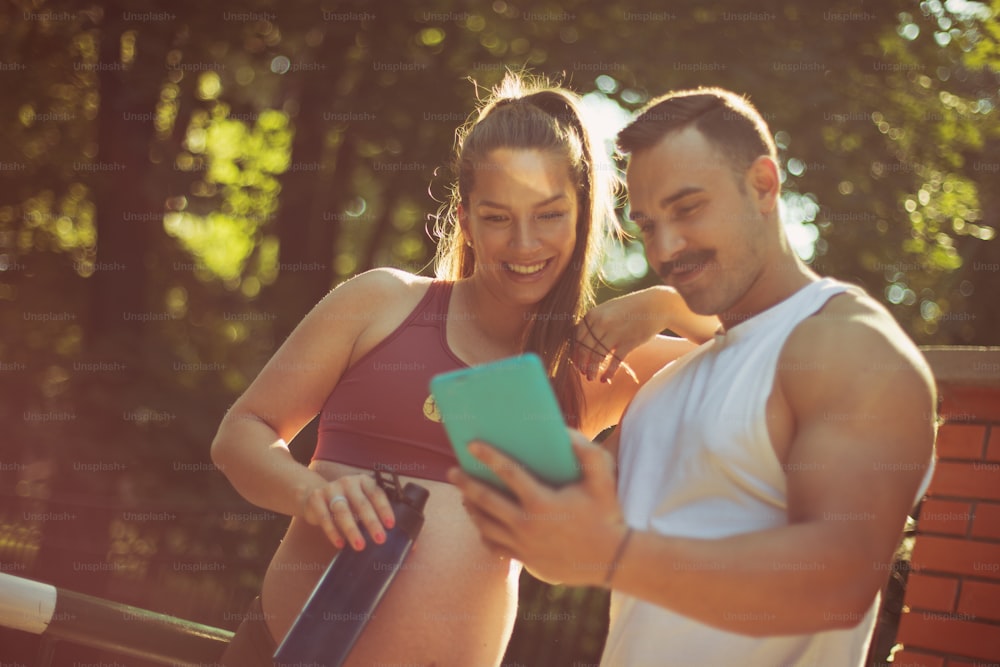 Sports couple standing outside and using digital tablet.