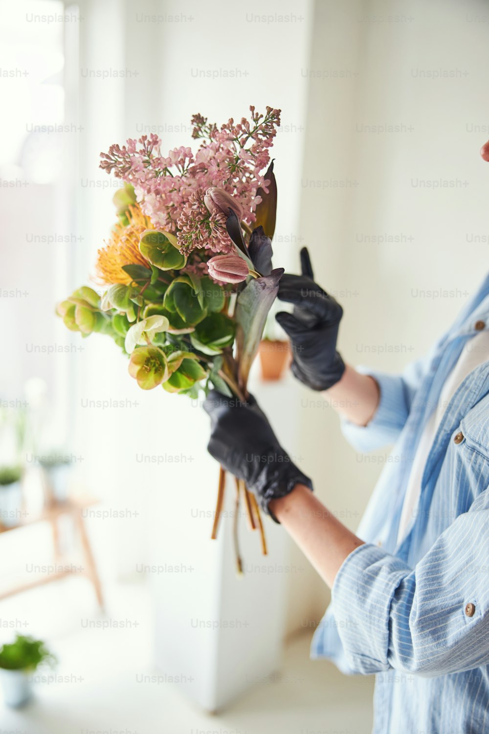 Foto recortada de una mujer con guantes de nitrilo sosteniendo un ramo de hermosas flores mixtas