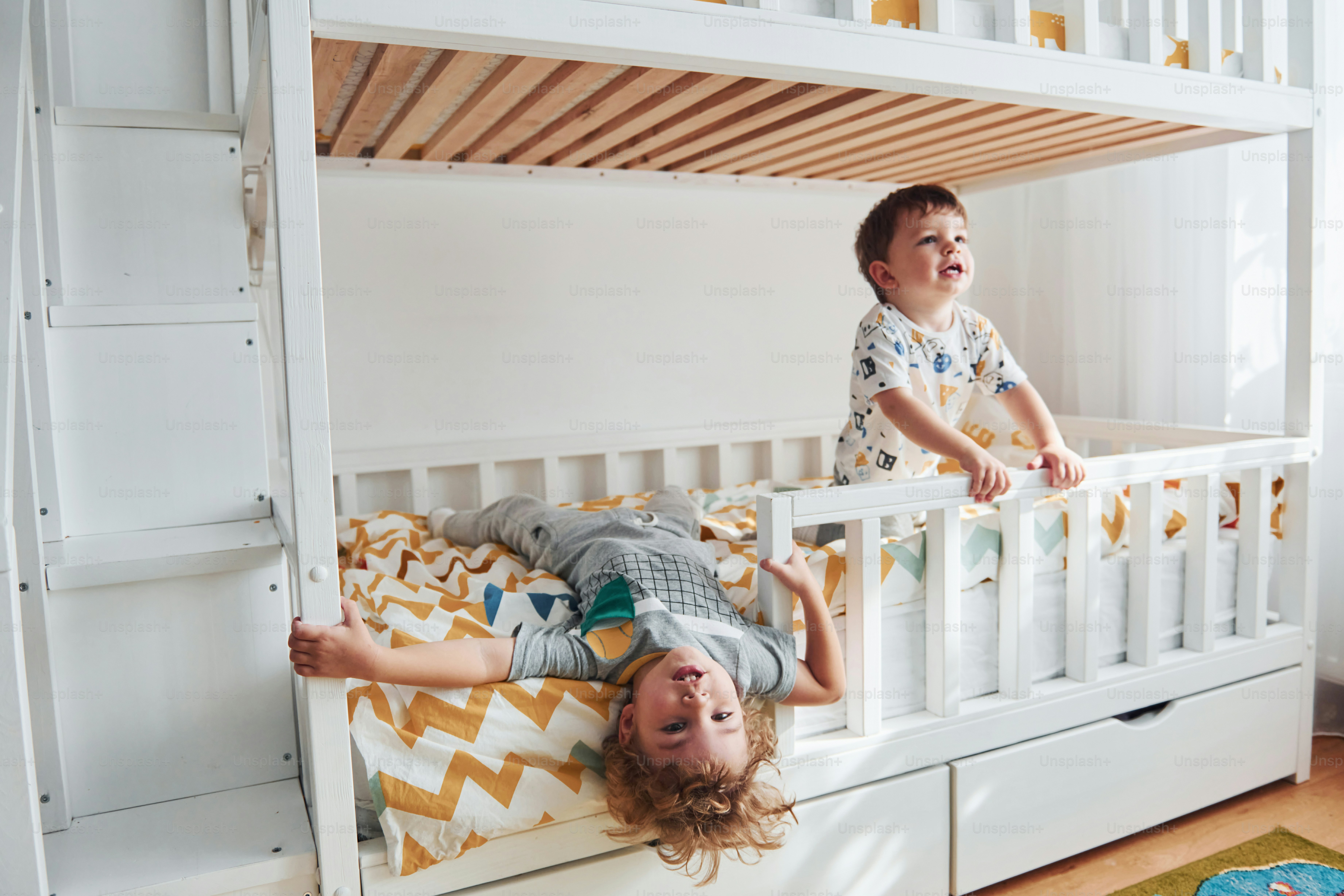 Two little boys resting and have fun indoors in the bedroom together.